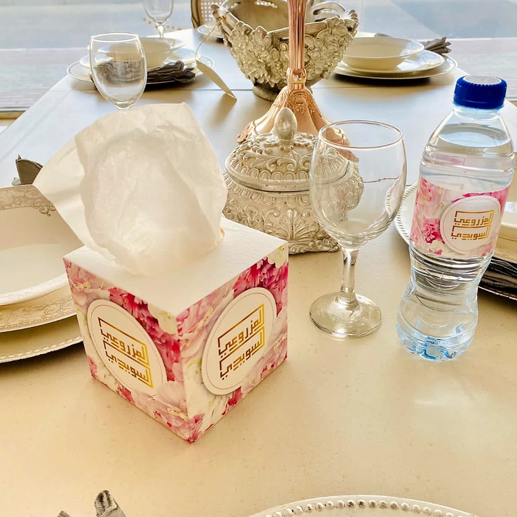 Customised paper tissue box and matching water bottle label on a set table