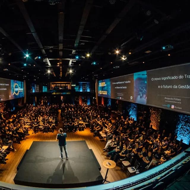 A speaker on stage in front of a large audience