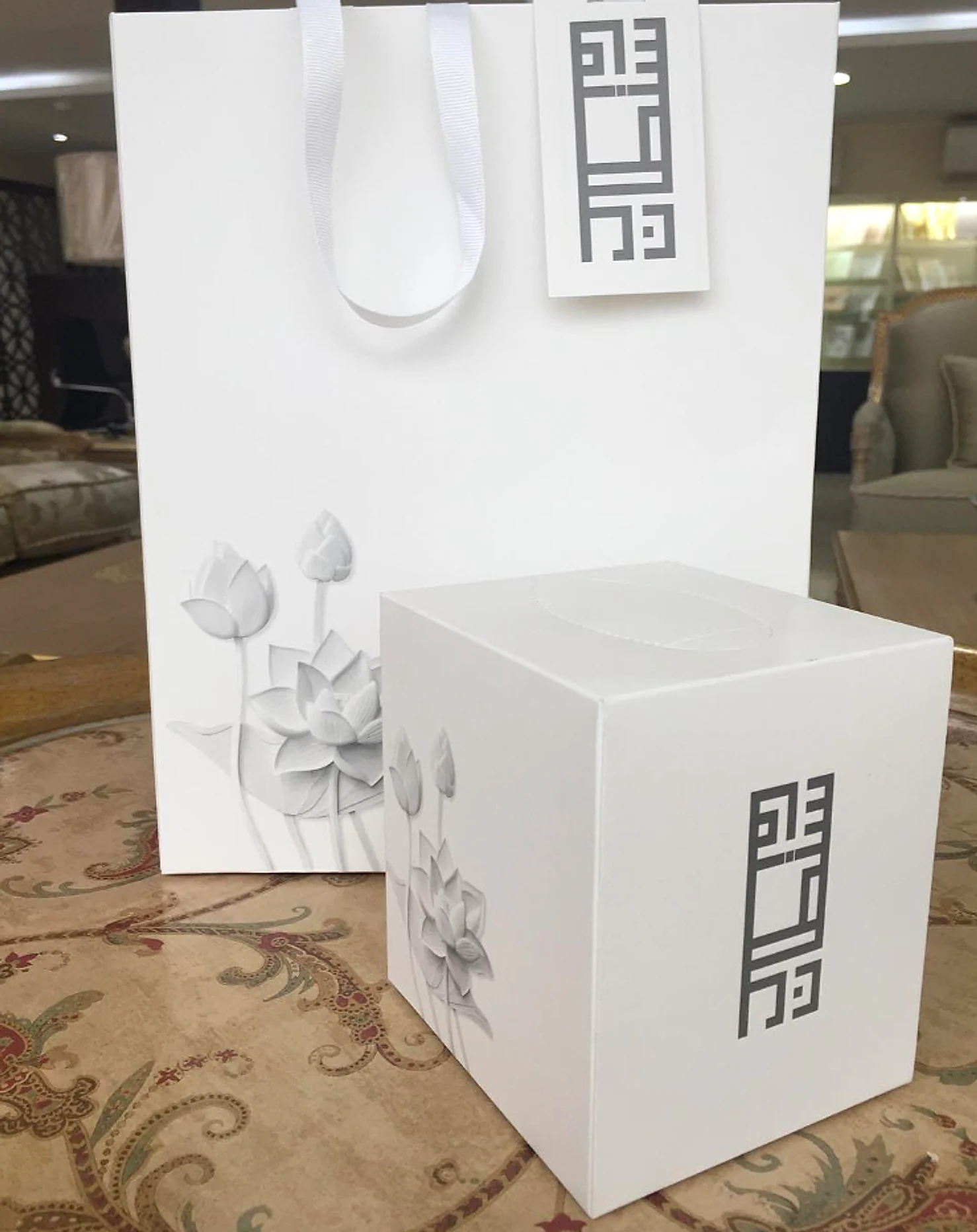 White gift bag and tissue box with a lotus relief and a printed monogram